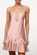 Quartz pink silk slip dress with oval emblem, lace edge neckline, ruffled hem
