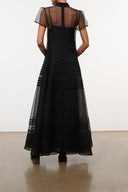 Back view of black sheer-panel maxi dress with high neck and tiered skirt