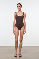 Dark one-piece swimsuit, square neckline, thin straps, high-leg cut
