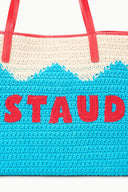 Blue knit tote bag with cream upper section and red handles, “STAUD” lettering in red