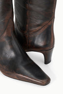 Close-up of dark brown distressed western boot shaft with stitched panels