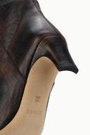Inside cuff of dark brown western boot with beige lining and small brand mark