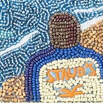 Close-up beaded patch detail reading “STUDIO” on blue and tan background