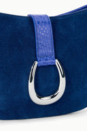 Cobalt suede shoulder bag close-up with silver ring buckle and textured strap