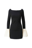 Black straight-neck mini dress with ivory ruffle cuffs and long sleeves