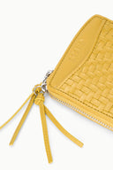 Goldenrod woven wallet corner with STAUD logo, zipper edge, and tassel