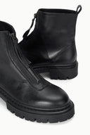 Black ankle boot with side-zip closure and chunky lug sole, front close-up.