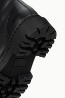 Black lug sole with deep tread and stitched side edge on black boot.