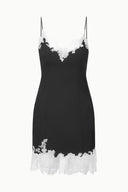 Black mini dress with white lace trim, scalloped V neckline and spaghetti straps