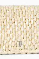 Cream woven bag front panel with small rectangular brand tag