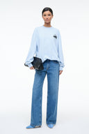 Light blue long-sleeve tee with chest logo graphic and wide sleeves