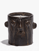 Brown ceramic candle holder with face motif and small wick in open top