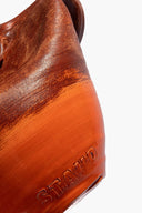 Sunken vase close-up with glazed logo on orange base and dark brown textured exterior