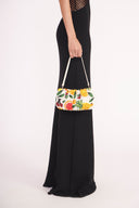 Beaded fruit bean bag purse with woven top handle, shown side-held on model