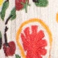 Close-up of beaded fruit motif with orange and red tones on cream fabric